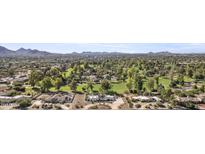 Expansive aerial view of a luxurious home, a golf course, and the desert landscape with mountains in the background at 10804 N 60Th Pl, Scottsdale, AZ 85254