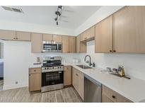 Modern kitchen featuring stainless steel appliances, light wood cabinets, and sleek white countertops at 2130 W Cindy St, Chandler, AZ 85224