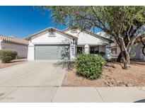Charming single-story home featuring a gray two-car garage and a well-maintained front yard with mature landscaping at 513 S 115Th Dr, Avondale, AZ 85323