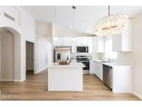Bright, open kitchen with stainless steel appliances, white cabinets, island, and stylish pendant lighting at 8343 W Audrey Ln, Peoria, AZ 85382