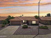 Charming single-story home with a well-manicured front yard featuring desert landscaping and a beautiful sunset at 9263 W Oraibi Dr, Peoria, AZ 85382