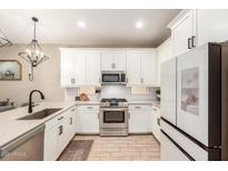 Modern kitchen features white cabinetry, stainless steel appliances, and a stylish faucet at 9624 E Thunderbolt Ave, Mesa, AZ 85212