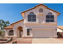 Two-story home featuring a terra cotta-colored roof, white stucco, arched windows, and a two-car garage at 1202 E Libby St, Phoenix, AZ 85022