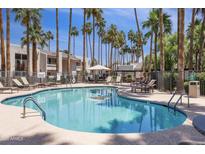 Inviting community pool with lounge chairs and shaded seating amid swaying palm trees at 7350 N Via Paseo Del Sur -- # N207, Scottsdale, AZ 85258