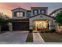 Charming two-story home with a well-manicured lawn, brick driveway, and a cozy front porch with stylish furniture at 20576 W Briarwood Dr, Buckeye, AZ 85396