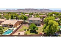 An aerial shot of a backyard featuring a sparkling pool, a fire pit, green grass, and mature trees at 2116 W Fawn Dr, Phoenix, AZ 85041