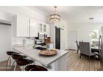 Modern kitchen features white cabinets, stainless steel appliances, a breakfast bar, and an adjacent dining area at 8835 W John Cabot Rd, Peoria, AZ 85382