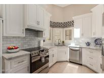 Updated kitchen featuring marble backsplash, white cabinets, and stainless steel appliances at 13041 S 45Th Pl, Phoenix, AZ 85044