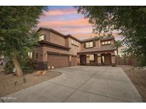 Gorgeous two-story home with a three-car garage, lush landscaping, and a warm, inviting facade at sunset at 14517 W Cortez St, Surprise, AZ 85379