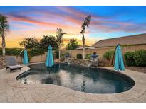Backyard pool area features stone waterfall, travertine decking, and lush landscaping for a resort-style living experience at 19748 E Walnut Rd, Queen Creek, AZ 85142