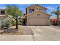Tan two-story home featuring a two-car garage, desert landscaping, and a brick paver walkway to the front door at 25409 N 40Th Ln, Phoenix, AZ 85083