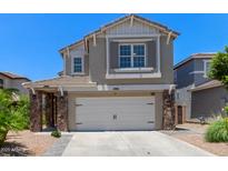 Two-story home with a two-car garage, stone accents, and a well-maintained front yard on a sunny day at 3692 N 292Nd Dr, Buckeye, AZ 85396