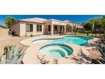 Private backyard features a sparkling pool and spa surrounded by tasteful landscaping and secure fencing at 4520 N 151St Dr, Goodyear, AZ 85395