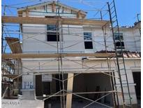 Exterior of home under construction featuring white facade, windows, two-car garage, and temporary scaffolding at 5851 E Covey Ln, Phoenix, AZ 85054