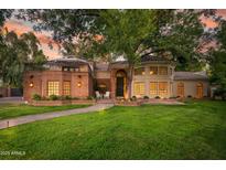 Charming home featuring lush landscaping, manicured lawn, brick accents, and inviting outdoor seating at the front door at 8219 S Pecan Grove Cir, Tempe, AZ 85284