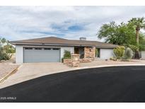 Charming single-story home with a stone accent wall, desert landscaping, and an attached two-car garage at 9039 N Concho Ln, Phoenix, AZ 85028
