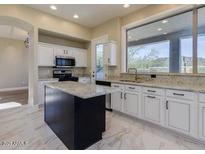 Bright kitchen with white cabinets, a black island, and marble floors, offering a stylish and functional space at 3634 N Desert Oasis --, Mesa, AZ 85207