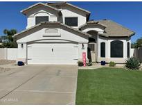 Charming two-story home with a well-maintained lawn and a two-car garage, under a sunny sky at 2934 S Woodruff Cir, Mesa, AZ 85212