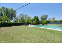 Relaxing backyard featuring a pool, lush green grass, mature trees, and ample privacy, perfect for outdoor entertaining at 325 W Loma Ln, Phoenix, AZ 85021