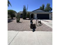 Landscaped front yard with desert plants, gravel, and decorative wagon wheel, showcasing southwest curb appeal at 8133 W Mclellan Rd, Glendale, AZ 85303