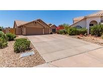 Charming home exterior featuring a wide driveway, three-car garage, and desert landscaping with lush flowering bushes at 10931 N 129Th Way, Scottsdale, AZ 85259