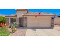 Charming single-story home featuring a two-car garage, desert landscaping, and an American flag at 22543 W Cocopah St, Buckeye, AZ 85326