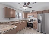 An eat-in kitchen featuring stainless steel appliances, tile counters, and warm cabinets at 3722 W Hadley St, Phoenix, AZ 85009
