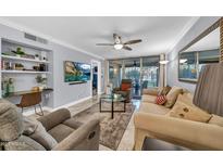 Open-concept living room with tile flooring, ceiling fan, built-in shelves, and sliding glass doors to the patio at 7625 E Camelback Rd # B138, Scottsdale, AZ 85251