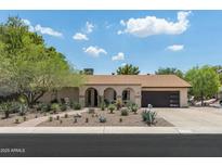 Charming single-story home with desert landscaping, arched entryway, and spacious three-car garage at 2301 E Sunnyside Dr, Phoenix, AZ 85028
