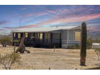Single-story home featuring a covered porch and desert landscaping with beautiful desert sunsets at 50525 W Whirly Bird Rd, Maricopa, AZ 85139