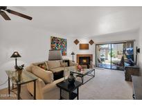 Bright living room features a fireplace, ceiling fan, and sliding glass door to the outdoor space at 8651 E Royal Palm Rd # 121, Scottsdale, AZ 85258