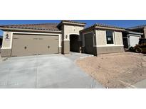 Beautiful home exterior featuring a three-car garage, neutral tones and a well-manicured lawn at 18717 N 267Th Dr, Buckeye, AZ 85396