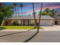 Charming single-story home featuring lush green lawn, palm trees, and desert landscaping at 5127 E Tamblo Dr, Phoenix, AZ 85044