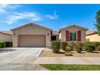 Charming single-story home featuring a well-maintained yard, red window shutters, and a two-car garage at 9738 E Tumeric Ave, Mesa, AZ 85212