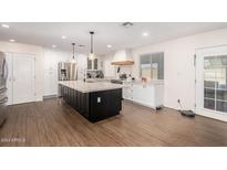 Spacious white kitchen with stainless steel appliances, large island, and wood-look tile flooring at 12043 N 46Th Ave, Glendale, AZ 85304