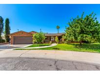 Charming brick home with a two-car garage, mature trees, and a well-manicured lawn at 125 E Loma Ln, Phoenix, AZ 85020