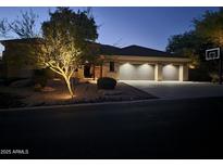 Charming home exterior showcases a well-lit front yard and a spacious three-car garage at 11320 E Winchcomb Dr, Scottsdale, AZ 85255