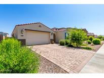 Charming single-story home with a well-manicured yard and brick paver driveway leading to a two-car garage at 12204 W Parkway Ln, Avondale, AZ 85323