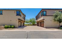 Townhome exterior featuring private garages and a shared brick paved driveway under a clear blue sky at 14870 W Encanto Blvd # 2006, Goodyear, AZ 85395
