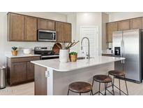 Modern kitchen with stainless steel appliances, wood cabinets, a white countertop island with stools at 1648 S 241St Ave, Buckeye, AZ 85326