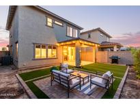 An inviting backyard with a seating area, lush lawn, and a covered patio with string lights for outdoor entertaining at 2067 N Marketside Ave, Buckeye, AZ 85396