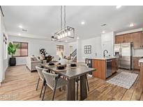 Dining area with modern chandelier, wood table set, and seamless flow to the kitchen and living room at 2067 N Marketside Ave, Buckeye, AZ 85396
