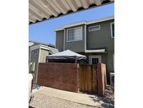 Two-story townhouse featuring muted green siding, a small porch, and a brick privacy fence with a wooden gate at 2301 E University Dr # 280, Mesa, AZ 85213