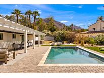 Inviting backyard pool area with covered patio, loungers, and mountain views under a clear blue sky at 4633 N 49Th Pl, Phoenix, AZ 85018
