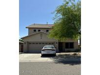 Two-story home featuring a neutral color palette, a two-car garage, and mature trees adding shade at 11633 W Jefferson St, Avondale, AZ 85323