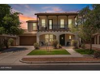Charming two-story home features a cozy balcony, arched entryway, lush landscaping, and inviting curb appeal at 3042 N Beverly Pl, Buckeye, AZ 85396