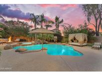 Backyard oasis with a large pool, waterfall, spa, lounge chairs, and lush landscaping at dusk at 824 W Whitten St, Chandler, AZ 85225