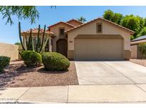 Charming single-story home with a two-car garage, desert landscaping, and a tile roof at 13373 W Boca Raton Rd, Surprise, AZ 85379