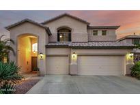 Charming two-story home with a three-car garage and desert landscaping is bathed in a warm sunset glow at 13636 W Calavar Rd, Surprise, AZ 85379