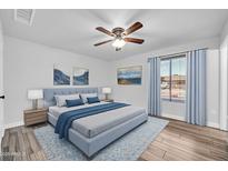 Comfortable bedroom features hardwood floors, ceiling fan, stylish decor, and lots of natural light at 3444 E Paradise Dr, Phoenix, AZ 85028